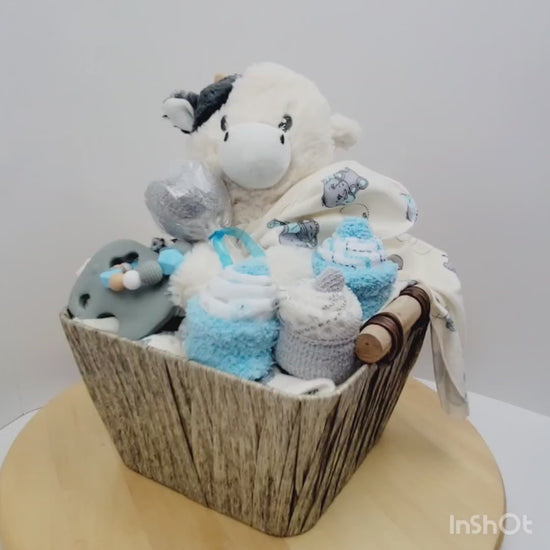 Vidéo 360 de l'Ensemble cadeau pour babyshower, panier remplis de couverture avec éléphant gris et bleu, un toutou de vache, des cupecakes en débarbouillettes et un jouet de dentition en silicone avec un éléphant gris.
